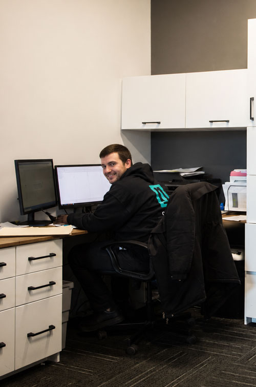 A smiling Cuisi-n-art employee at his workstation in the office